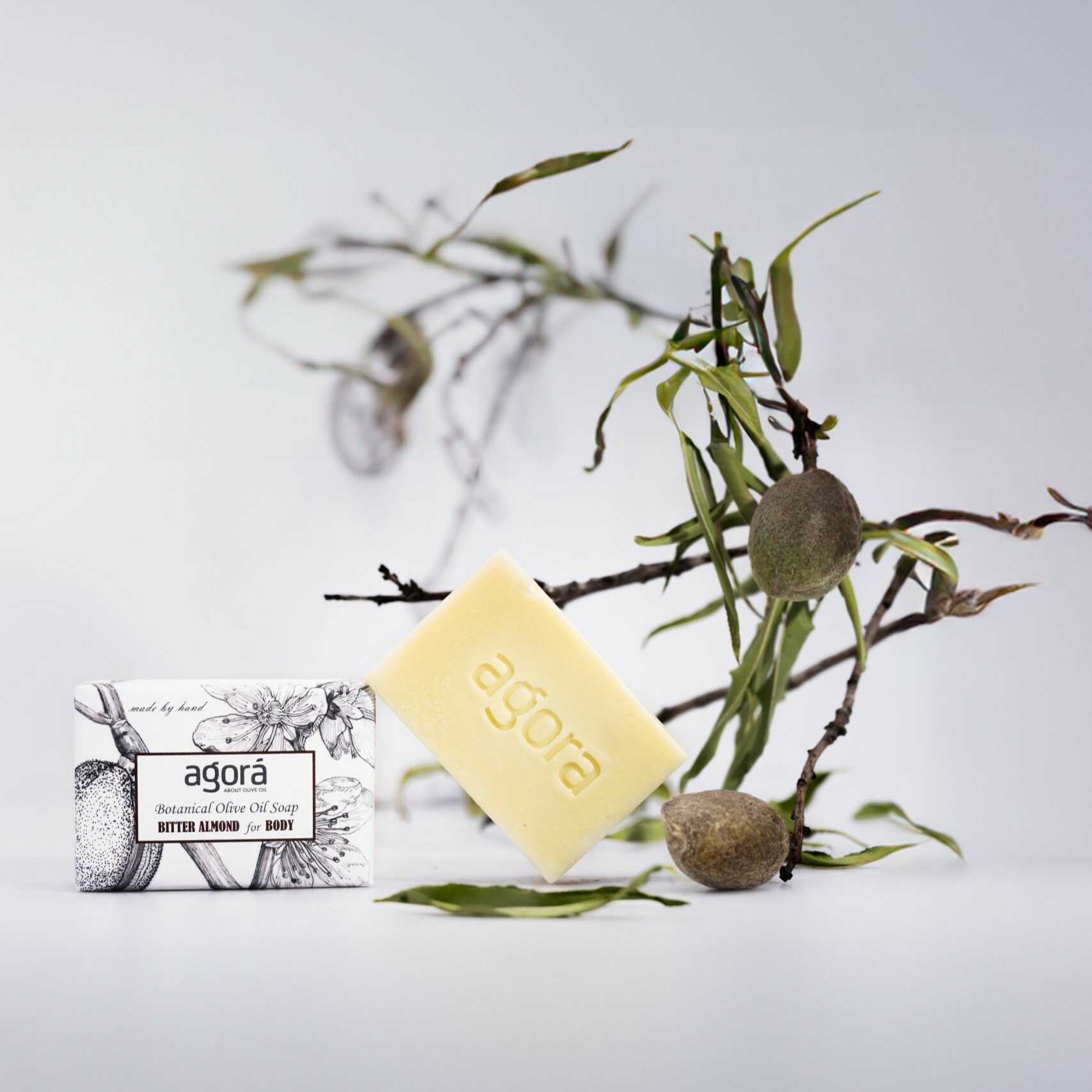 Agorá botanical olive oil soap with bitter almond for body care. Displayed with whole almonds and twigs, emphasizing its natural ingredients and gentle formulation.